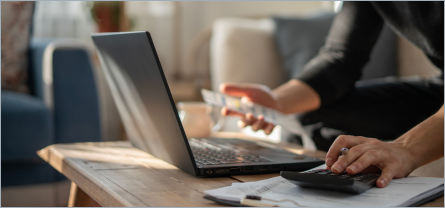 Person holding a phone and using a laptop.